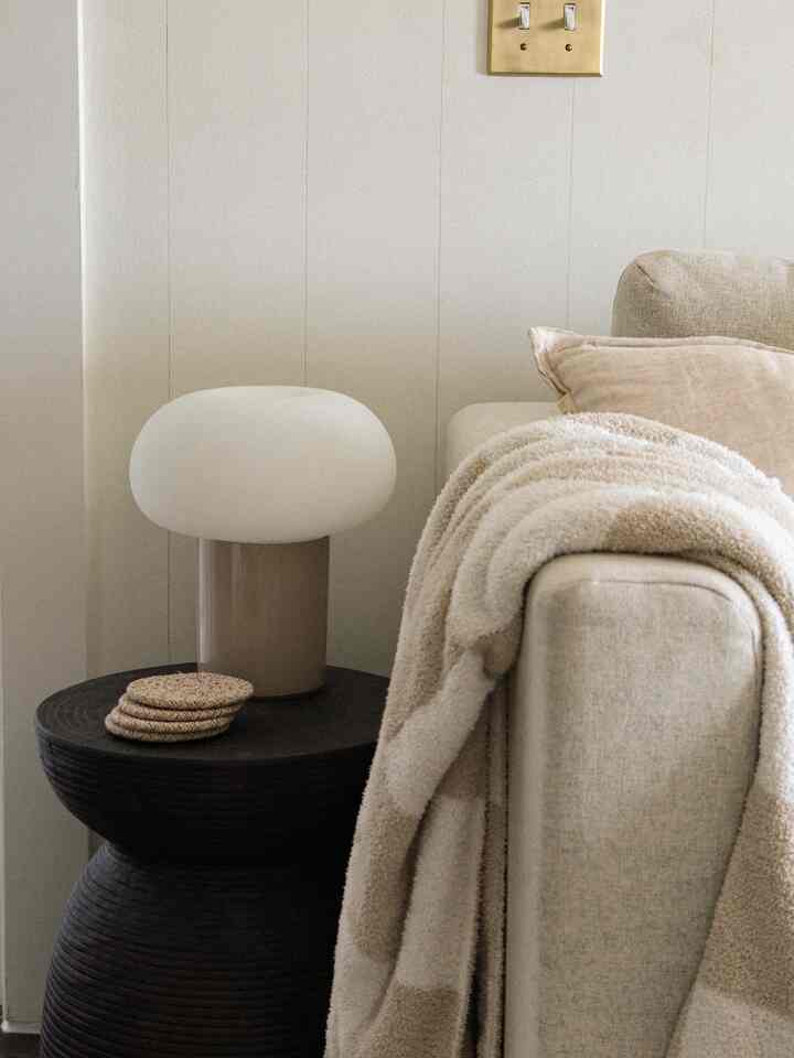 Beige and black toned living room featuring a beige sofa alongside a black side table with a rounded white lamp, creating a cozy atmosphere