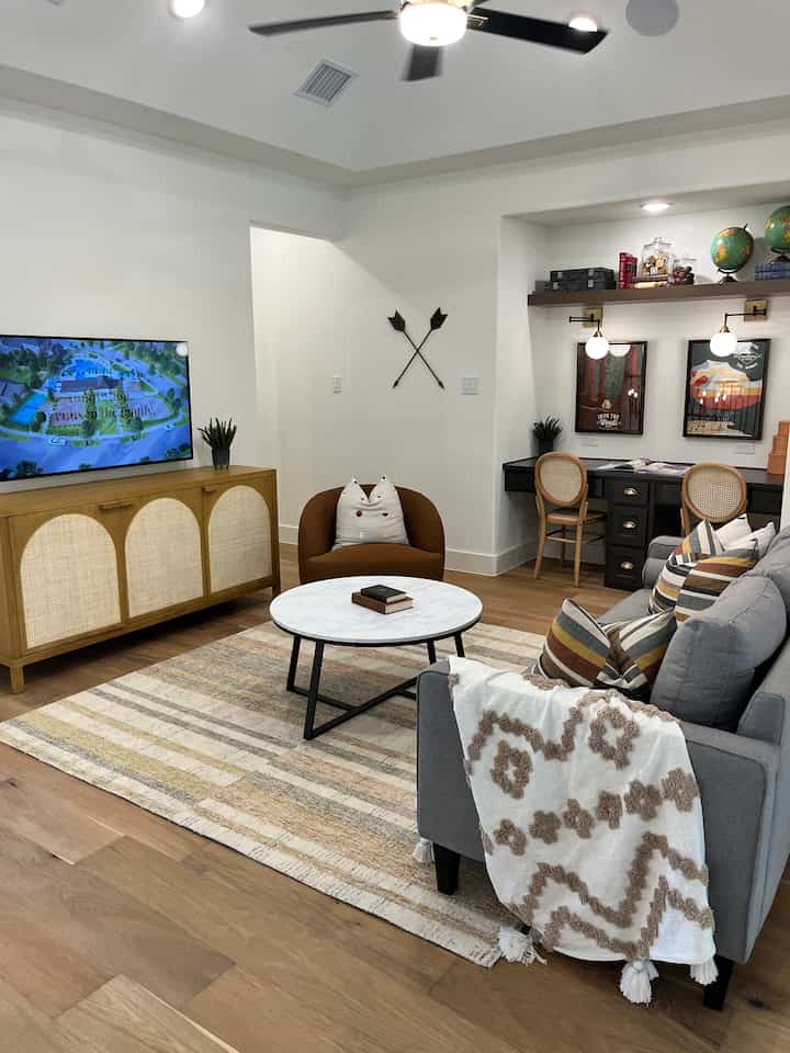 Natural color toned living room featuring gray sofa, round coffee table, and decorated desk nook in a Bohemian style