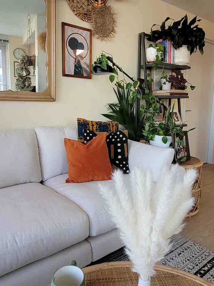 Light and natural toned living room featuring a white sofa, brown rattan coffee table, green plants, and bohemian decor