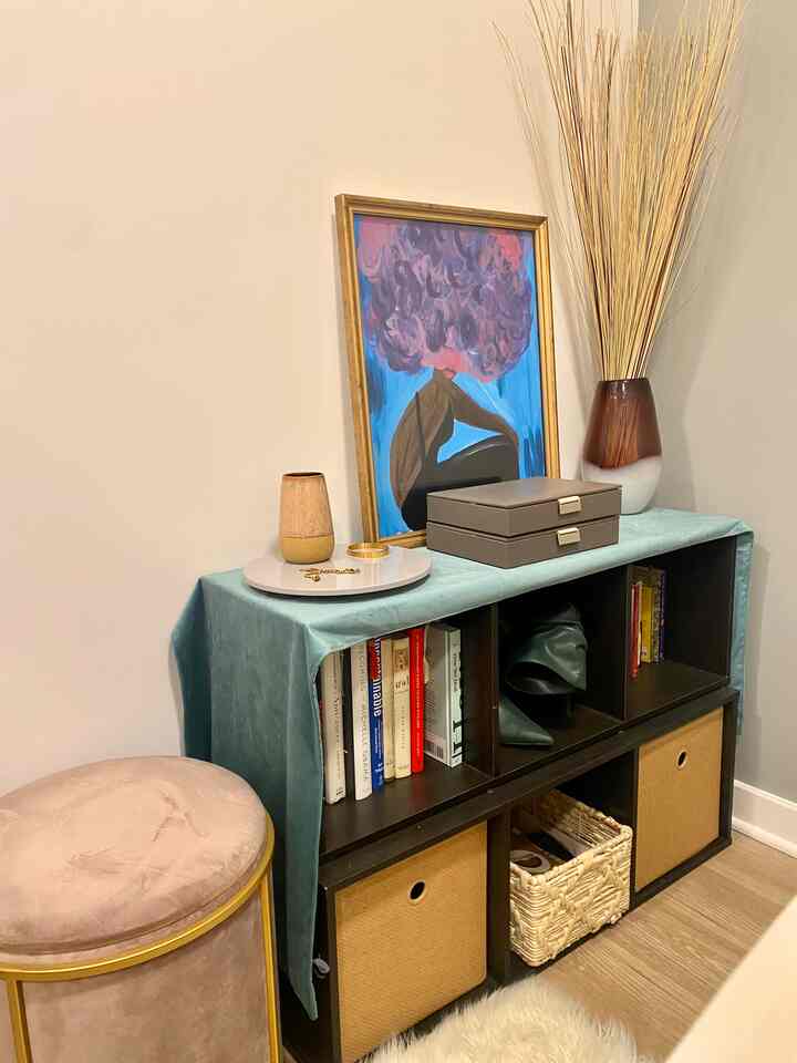 Natural tone studio apartment corner featuring a bookshelf with a table runner, creating a soft and cozy atmosphere