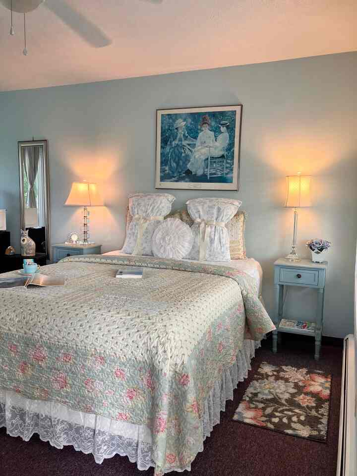 A cozy bedroom with lavender-toned walls and vintage bedding