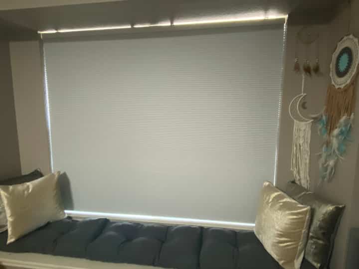 Beige and black tone window reading nook featuring cushions and bench seat with cozy atmosphere