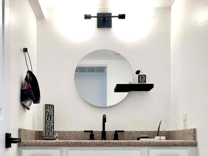 White and black toned bathroom featuring a round mirror and modern black fixtures with a clean atmosphere