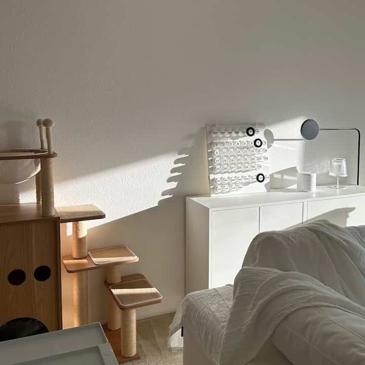 White and wood tone bedroom featuring a cat tower and clean storage unit creating a cozy atmosphere