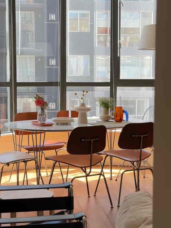 Natural tones and white dining room featuring wood tone chairs and vases on table, creating a modern and warm atmosphere
