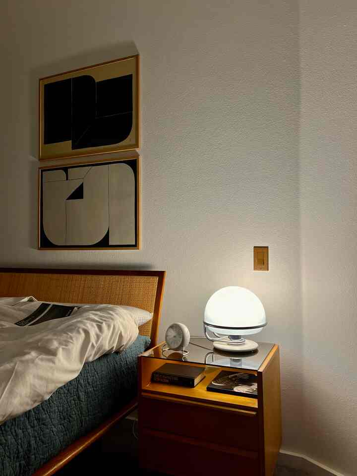 Brown-toned bedroom featuring wooden bed and nightstand with round clock and table lamp, creating a cozy atmosphere