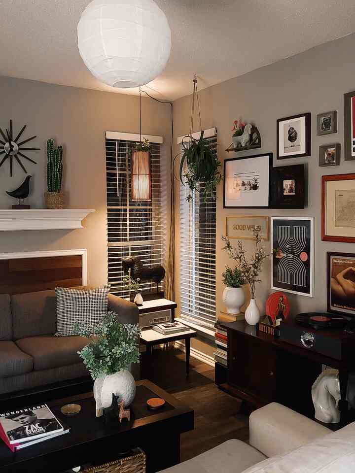 Warm brown and white toned living room featuring sofas, coffee table, plants, and framed wall art creating cozy atmosphere