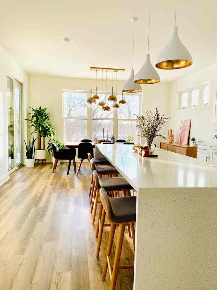 Modern kitchen and dining room with white and wood tones, featuring pendant lights and chandelier as focal elements