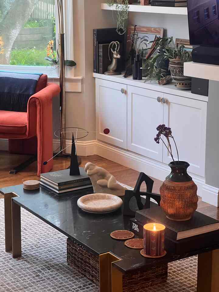 Dark brown floor living room featuring white cabinetry, red armchair, and black marble coffee table with decorative objets, creating a cozy atmosphere