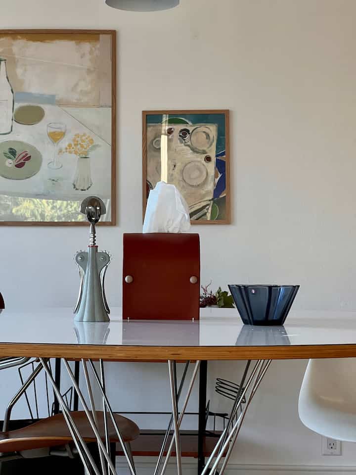 White and wood tone dining room featuring a modern dining table with a corkscrew and bowl, creating a simple atmosphere