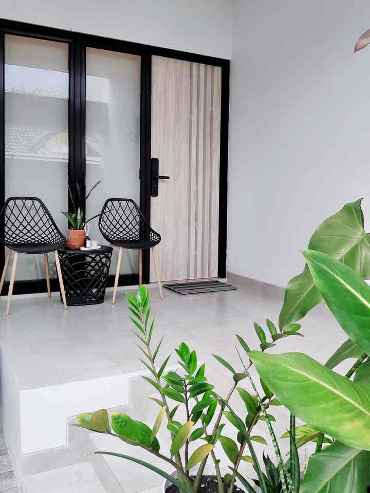 Natural toned and black modern industrial entrance area featuring two chairs, side table, and green plants as accents.
