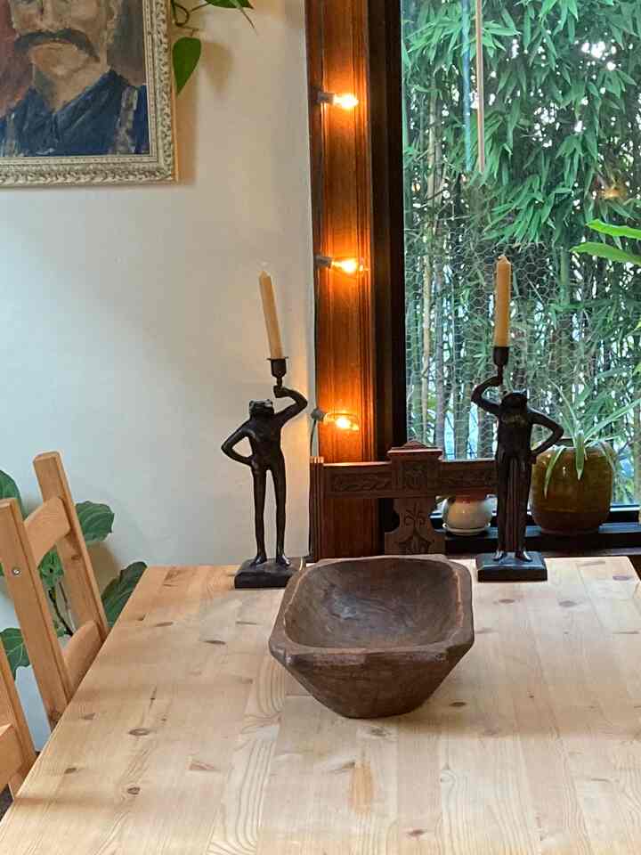 A soft wood-toned dining room featuring a wooden dining table and chairs with two brass frog candle holders, creating a natural atmosphere