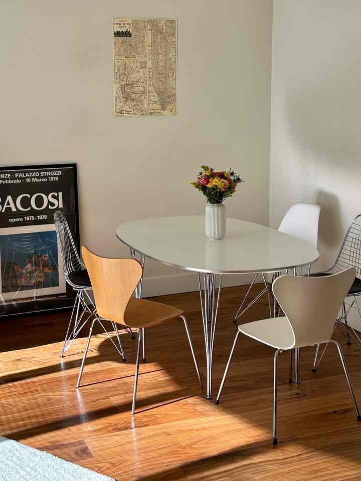 Natural dining room with white walls and wood-tone flooring, featuring a simple dining table and chairs
