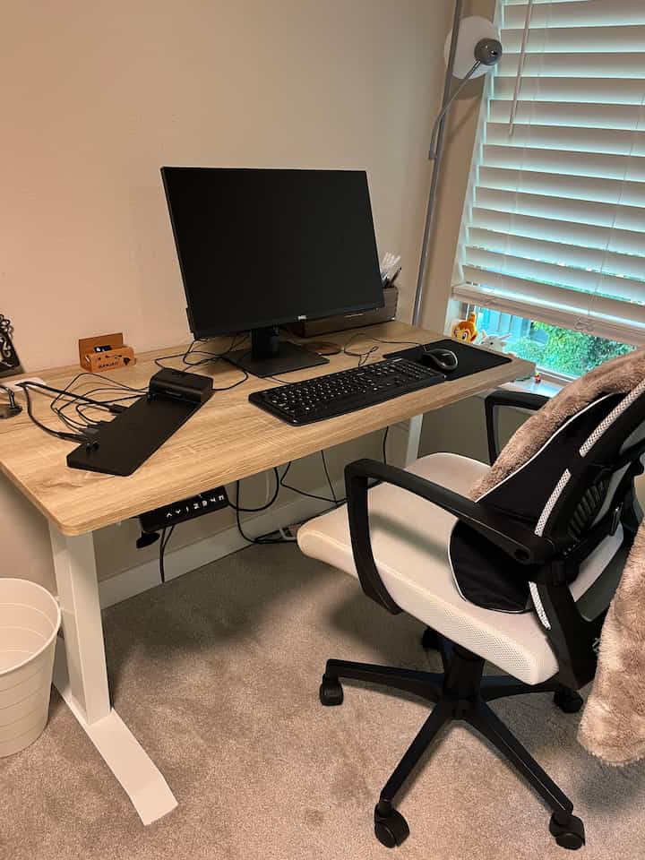 Natural-tone home office featuring electric height adjustable desk and ergonomic office chair with simple atmosphere