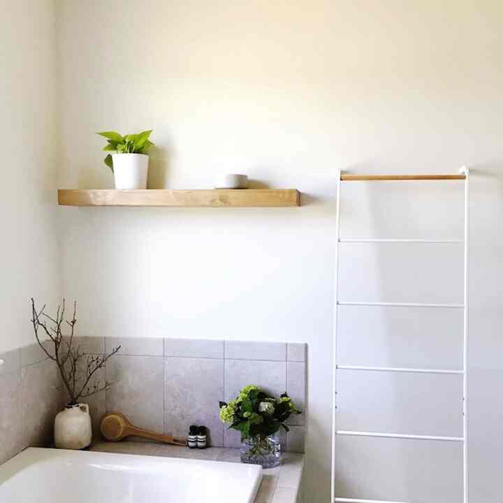 Warm white tone bathroom featuring wood shelf and towel rack with a simple and natural atmosphere