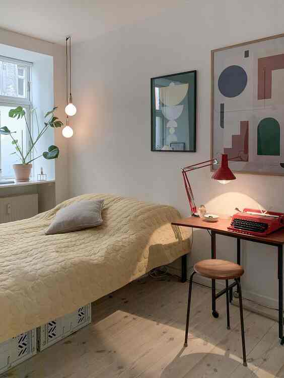 Yellow quilted bedroom with pendant lights by window and a red side table, featuring a simple and natural atmosphere