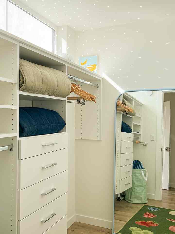 Bright and tidy walk-in closet in white and wood tones featuring a full-length mirror and efficient storage space