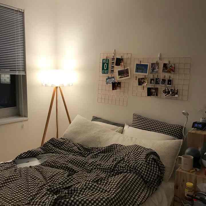 Cozy single household bedroom with white walls and wood tone furniture, featuring checkered bedding and photo wall grids