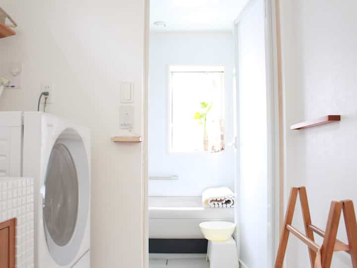 白を基調とした浴室と洗濯スペース、ドア越しに浴槽とタオルが見える清潔でコンパクトな空間