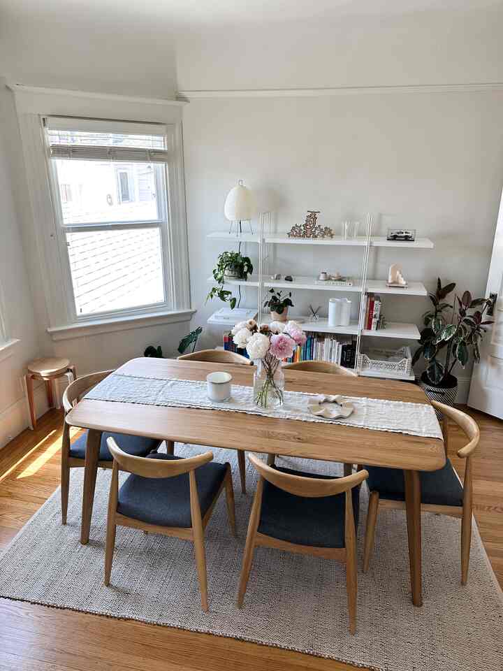 Bright white walls and wood-toned dining table with chairs in a natural dining room space