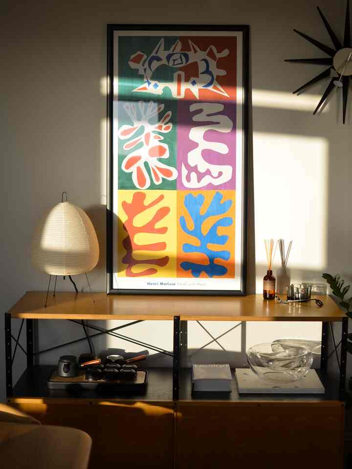 Warm golden-tone dining room featuring a natural wood sideboard and vintage Matisse framed print with soft lighting