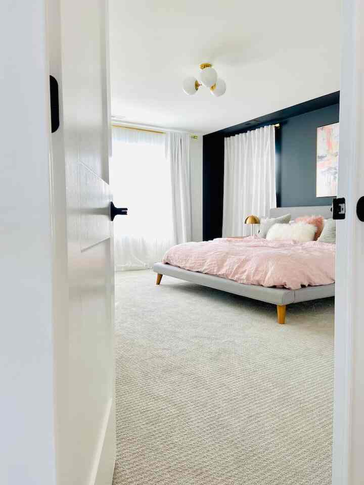 White and pink toned bedroom featuring a modern upholstered bed and curtains, creating a luxurious atmosphere