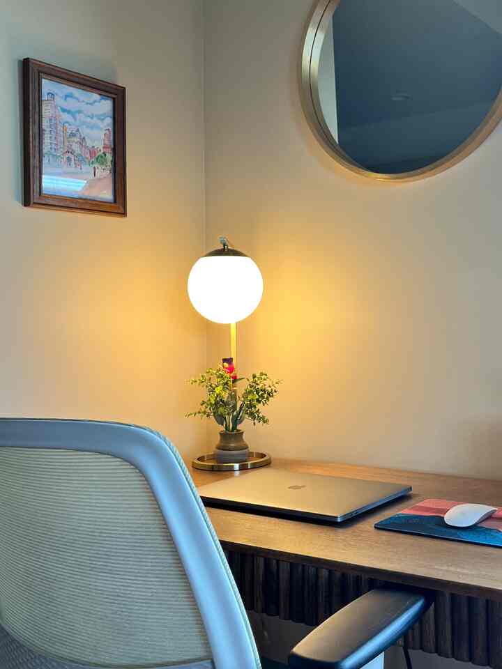 Warm wood tone and white home office corner featuring a laptop, table lamp, and comfortable office chair