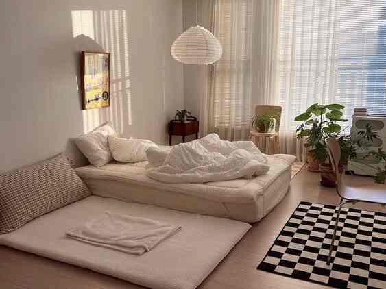 White-toned bedroom featuring transparent sheer curtains, a checkered rug, and natural plants with a cozy atmosphere