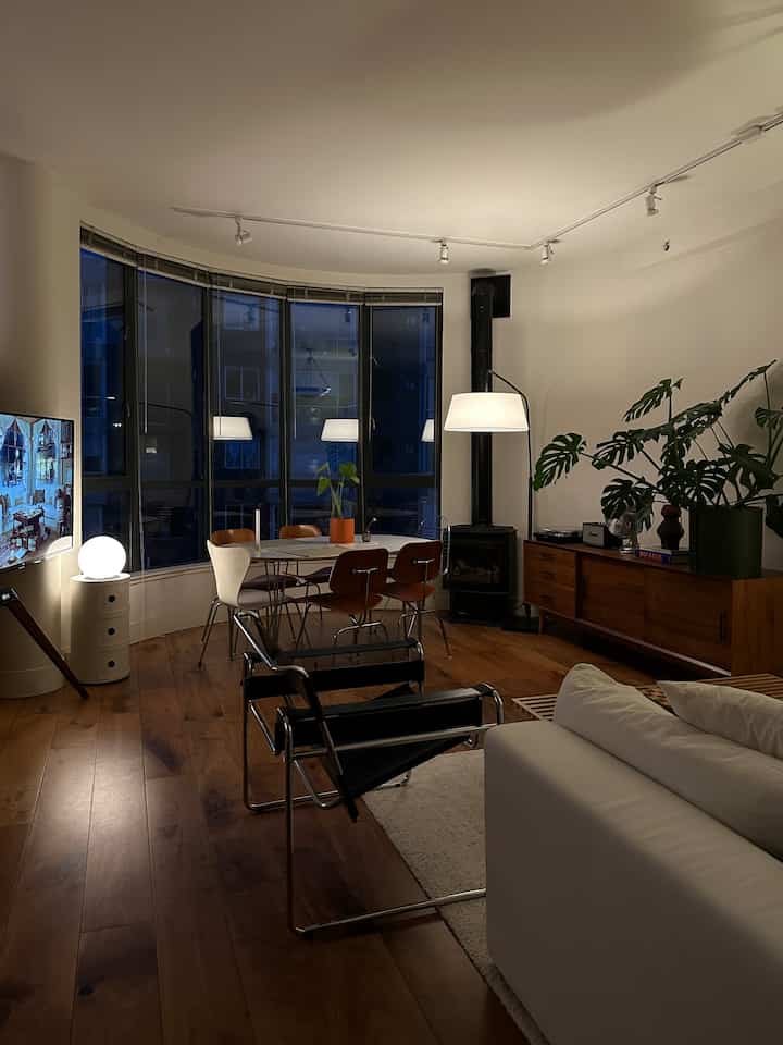Wood-toned floor and white sofa in a mid-century modern living room featuring a dining table with chairs, creating a cozy atmosphere