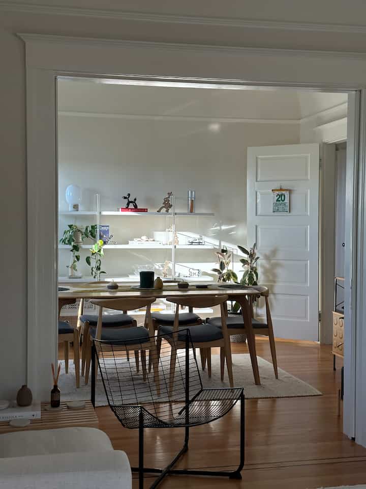 Modern dining room with white walls, wooden dining table and chairs, bathed in natural light