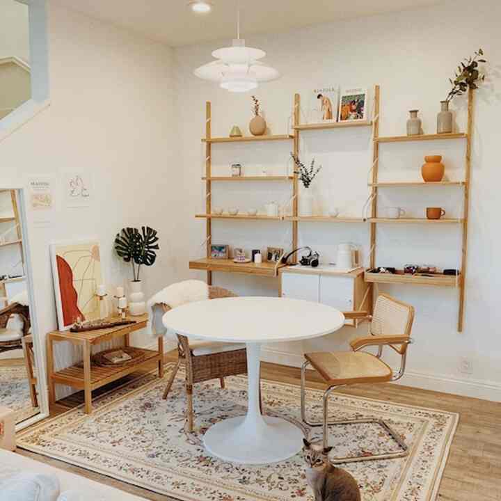 White and wood tone dining room with round table and rattan chairs in a cozy natural setting