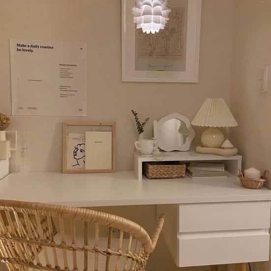 Natural-toned cozy workspace corner featuring a white desk and a rattan chair with soft lighting
