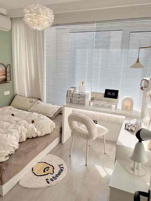 White and beige toned bedroom combined with home office, featuring simple furniture and pendant lighting in a clean layout