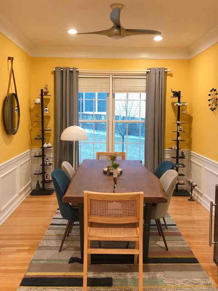 Bright yellow walled dining room featuring wood tone furniture and a natural modern atmosphere
