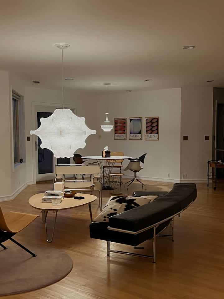 A mid-century modern living room in white and wood tones, featuring a modern sofa and round coffee table in a clean layout