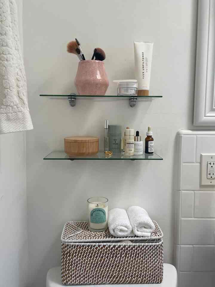 White and beige toned bathroom with glass shelves and towels, neat and charming small bathroom space