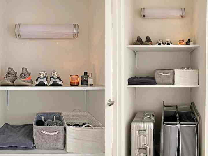 White and gray toned compact studio apartment storage space featuring shelves and baskets organized neatly