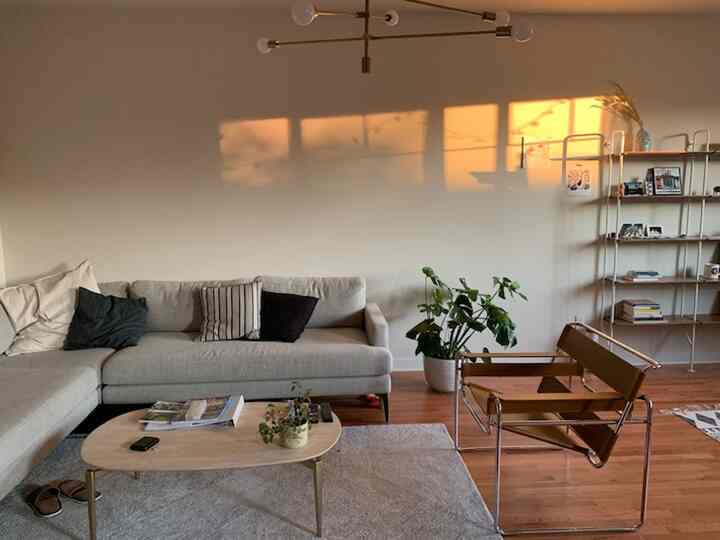 Warm beige and light brown toned living room featuring beige sectional sofa and modern armchair in cozy space