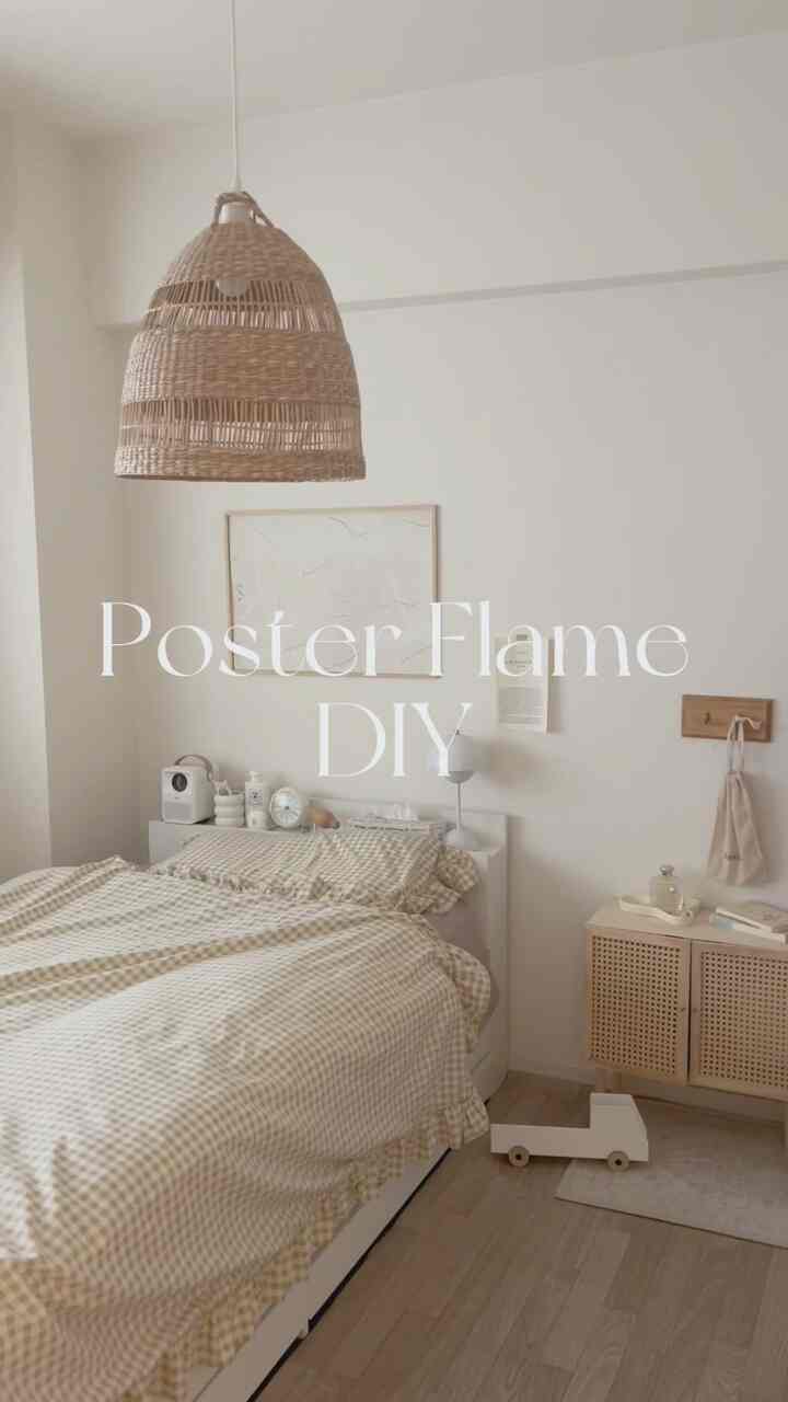 白とベージュ調の寝室、ナチュラル素材の照明とベッド、ナイトテーブル、ポスターが配置された雰囲気のあるインテリア