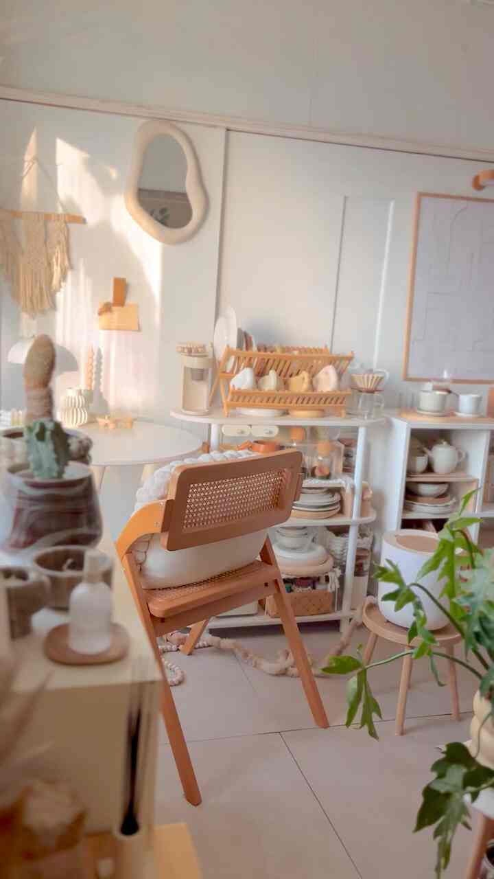 ベージュとナチュラルカラーのワンルームキッチン、木製の椅子と食器ラックが配置された雰囲気のあるインテリア