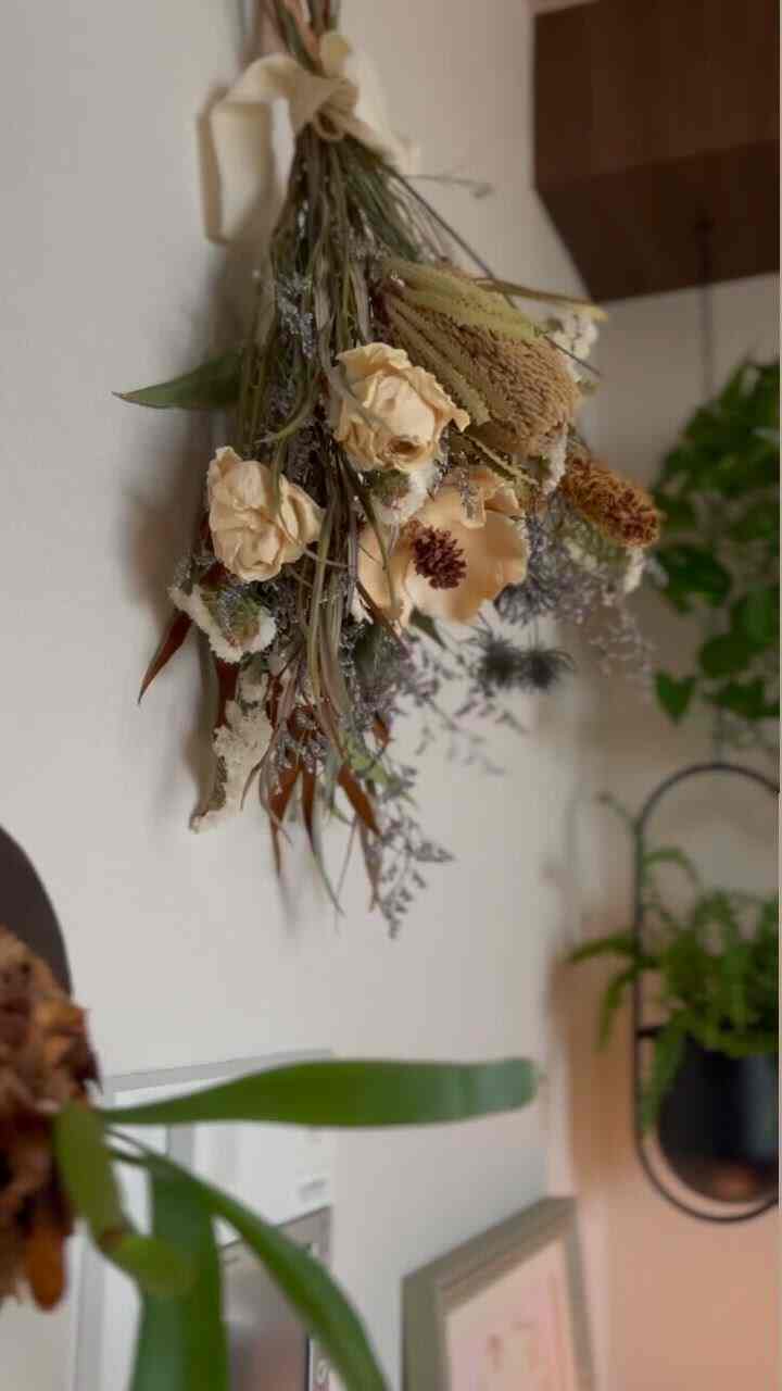 Natural tone interior with dried flowers hanging on wall and plants arranged, creating cozy atmosphere