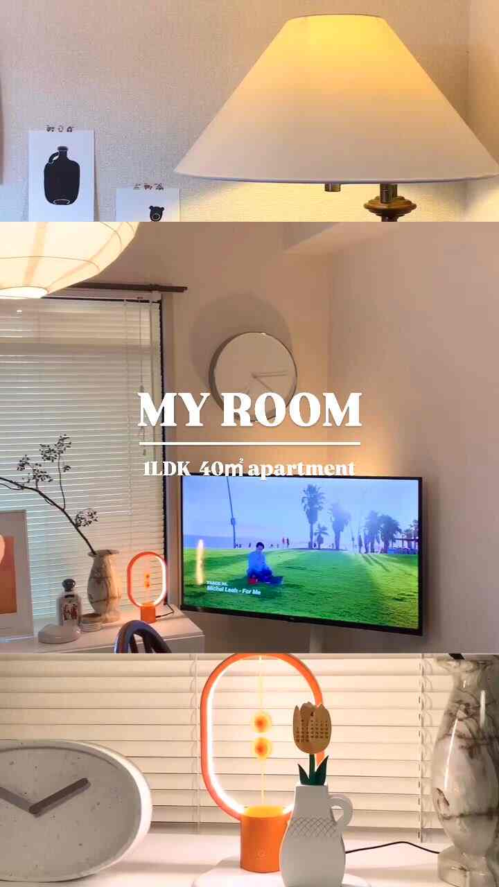 白とベージュのトーンの1LDKリビング、テレビ、テーブルランプ、壁時計、ブラインドが配置された北欧風の雰囲気のあるインテリア