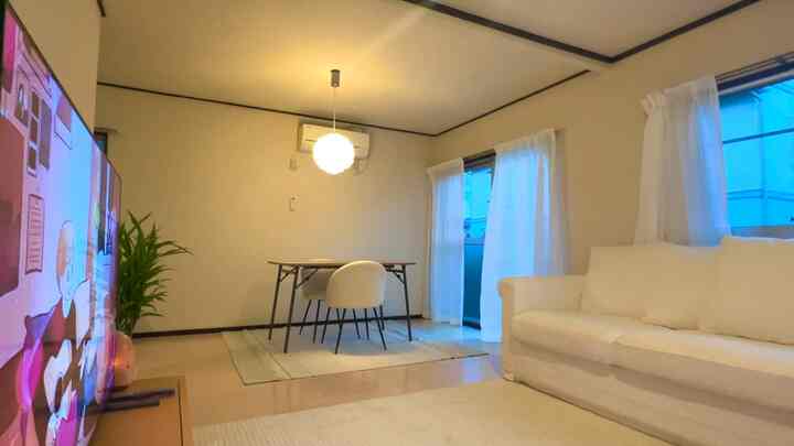 明るいホワイトとナチュラルカラーが調和する4人暮らしのリビング、ソファとダイニングテーブルが配置された落ち着いた空間