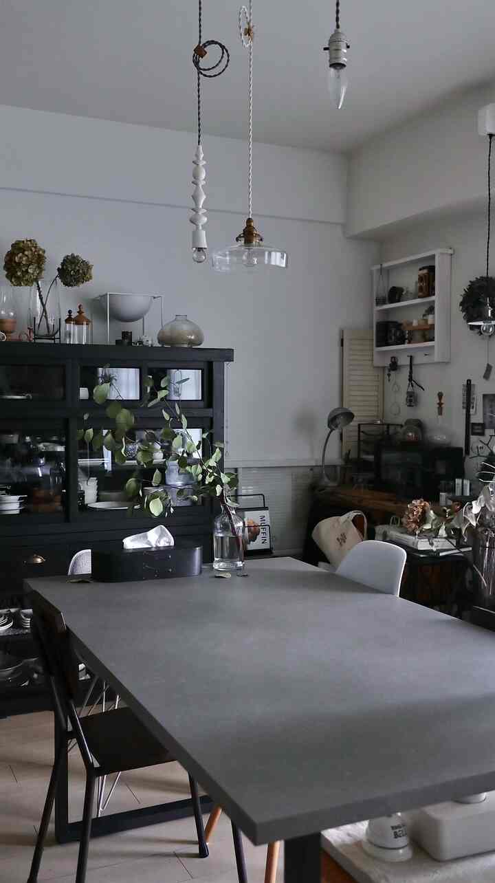 グレーの色調のダイニングルーム、中央に大きなグレーのダイニングテーブルと周囲に椅子が配置されたモダンでヴィンテージ感のあるインテリア