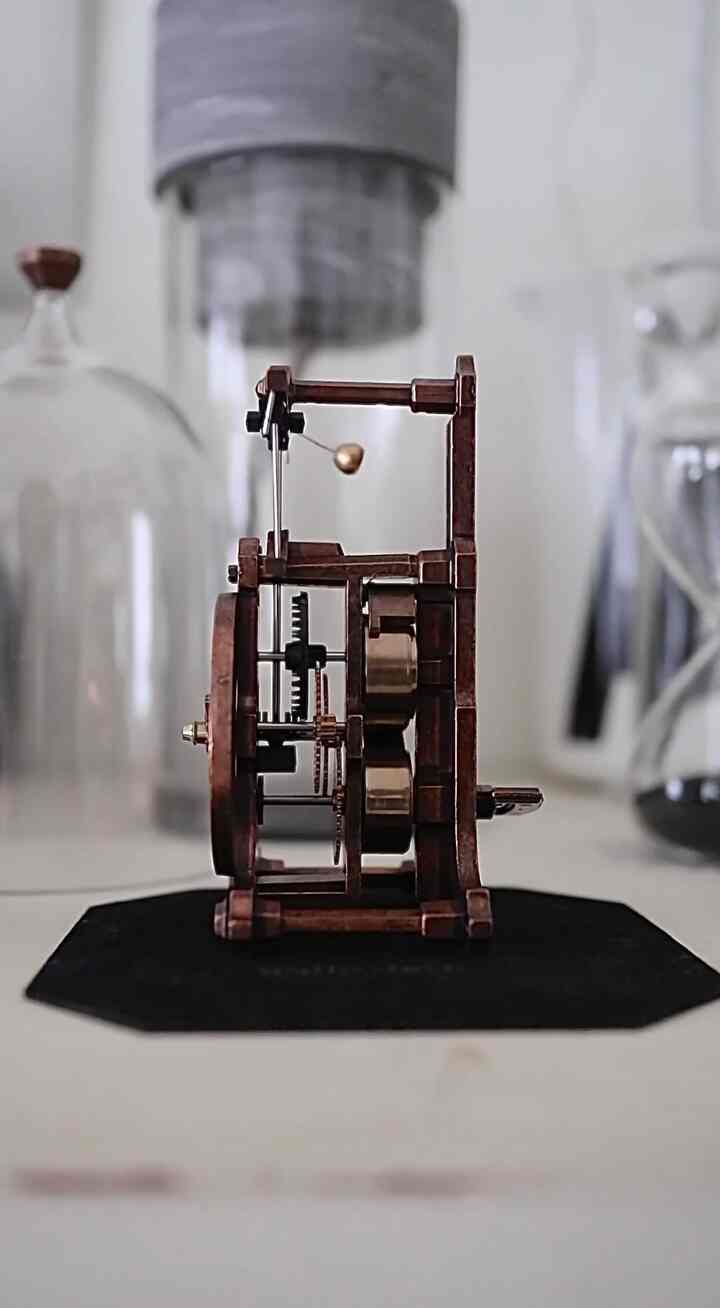 モダンな雰囲気のリビング、ゴールドのアクセントがある精巧な時計機構と透明なガラス製品が配置された印象的な空間