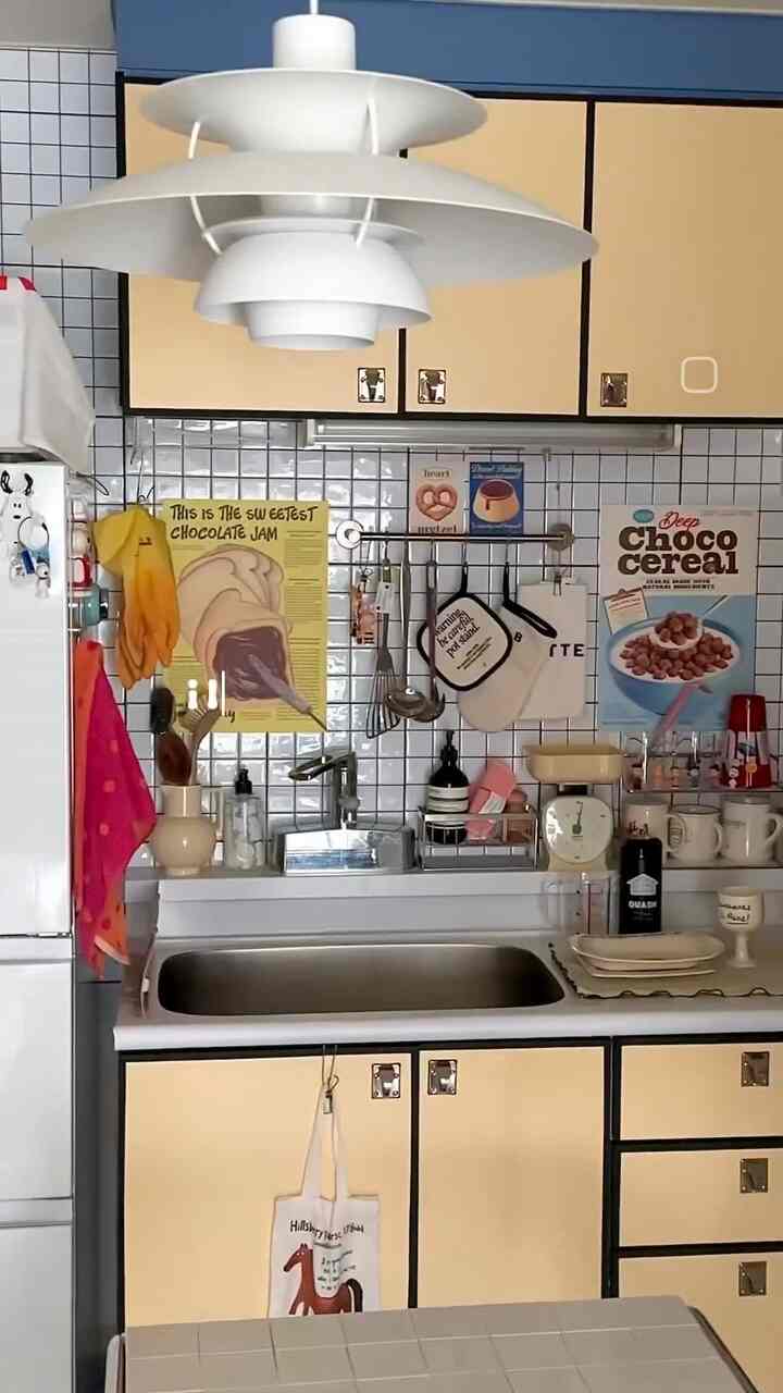 黄色と白を基調としたキッチン、中央にペンダントライトが配置された雰囲気のあるインテリア