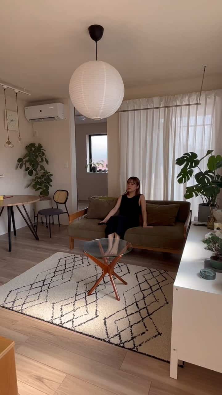 Natural color and wood tone living room featuring fabric sofa, glass coffee table, and plants in cozy atmosphere