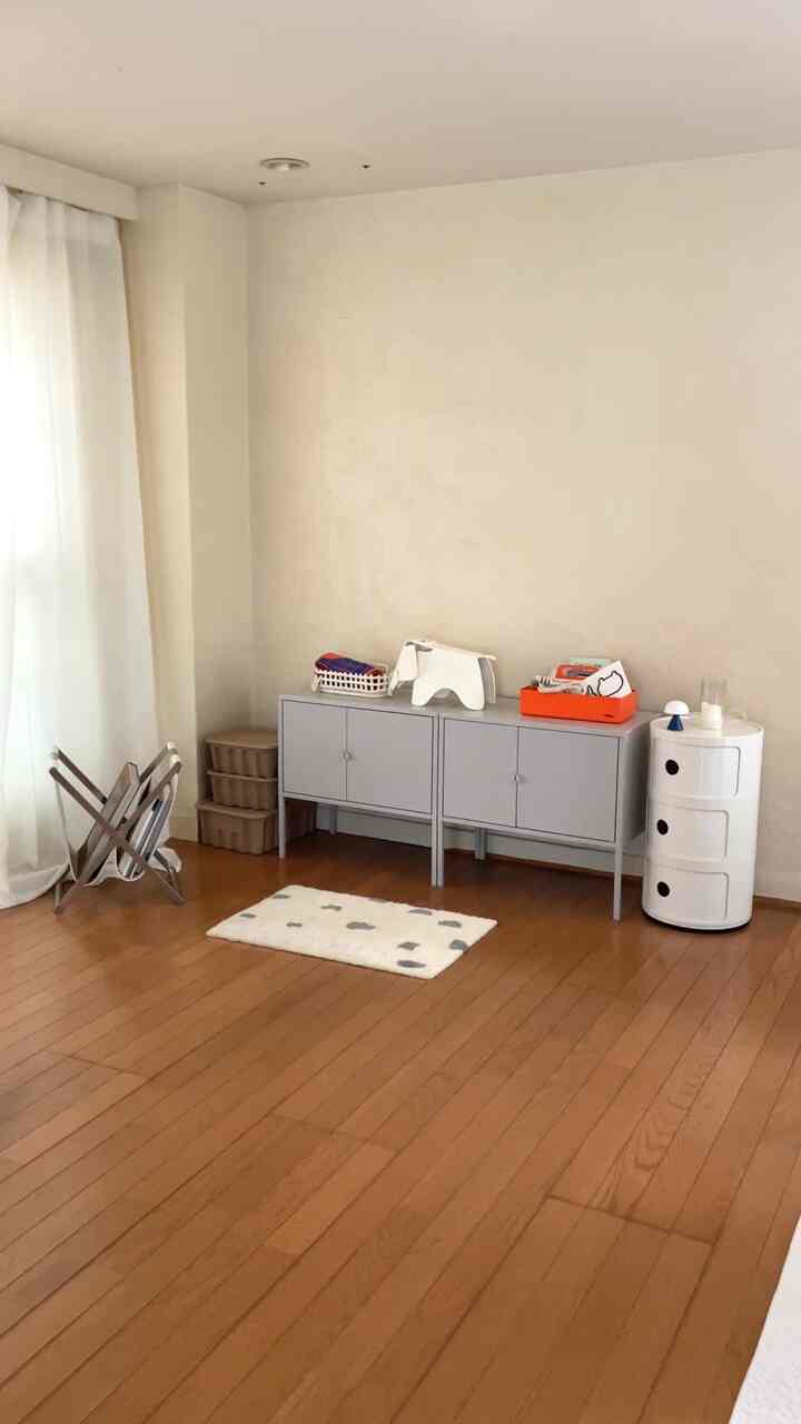 ホワイトとブラウンの色調の1LDKリビング、収納家具が配置され、ミニマルで落ち着いた雰囲気の空間