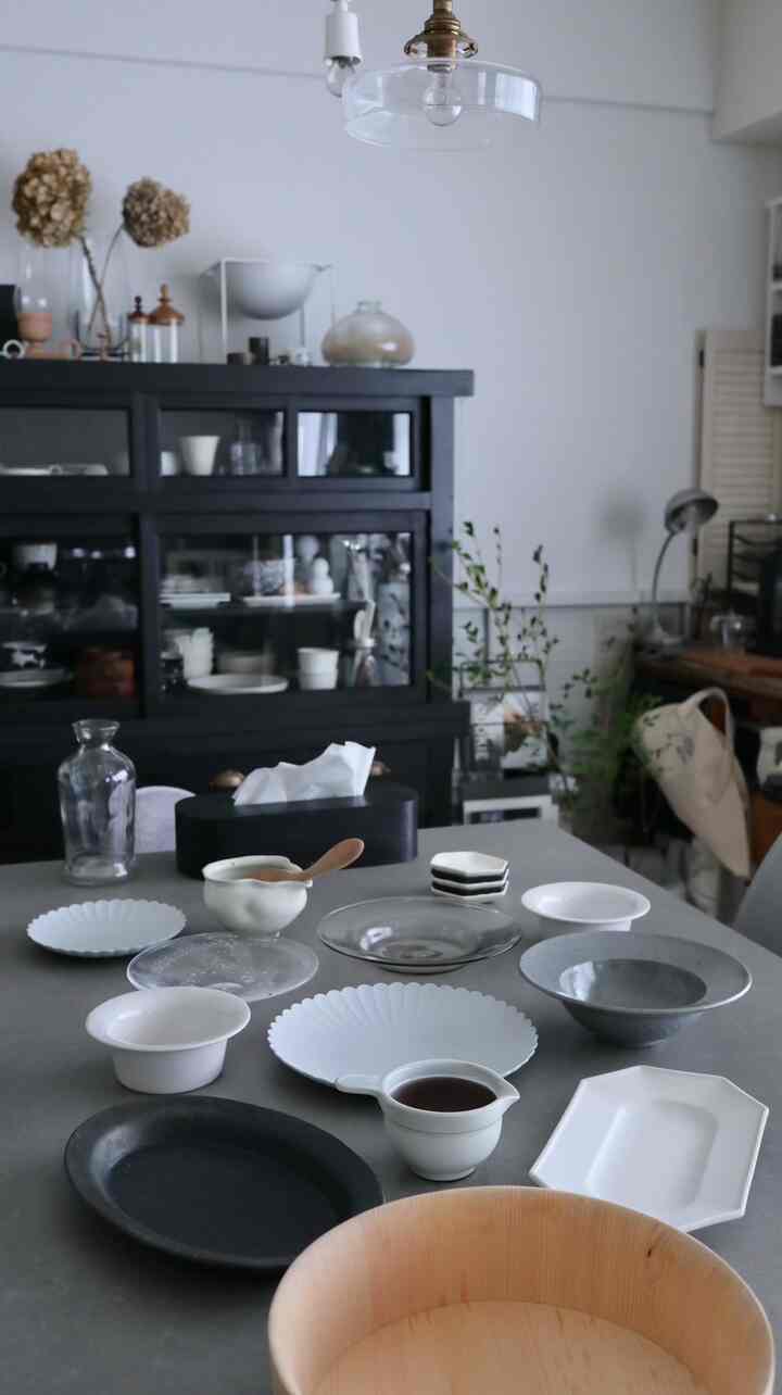 Natural-toned dining room in white and black hues featuring diverse bowls and wooden tableware for a hand-rolled sushi setting