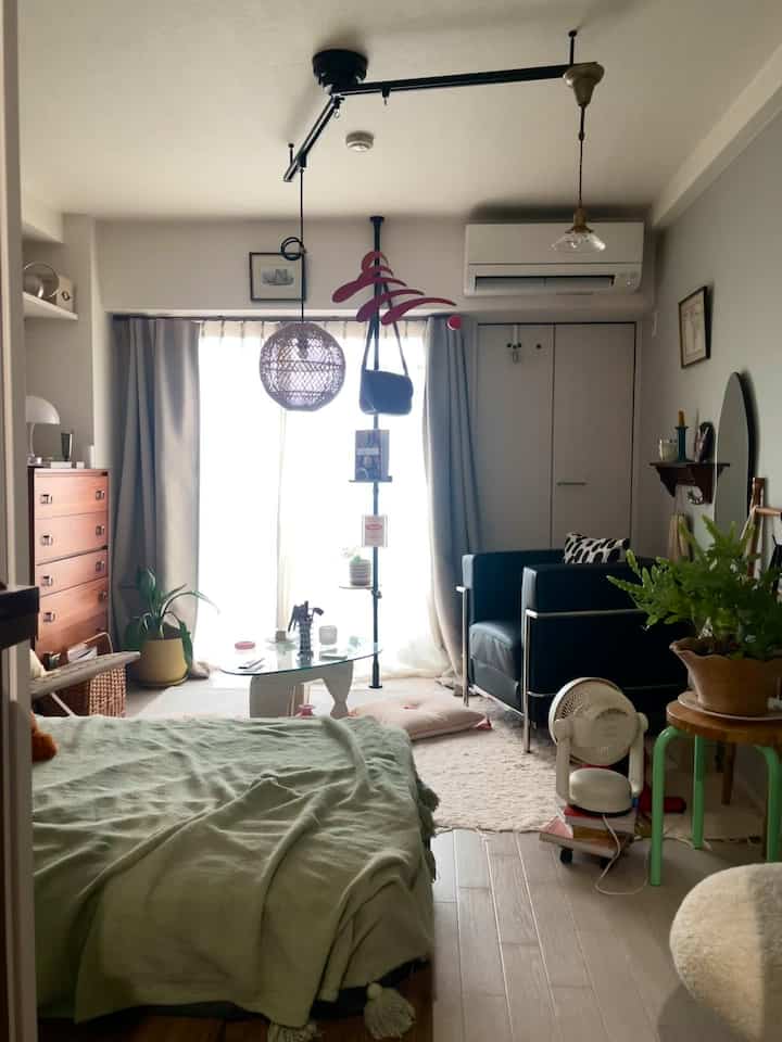 Natural tone single household 1K living room featuring bed, armchair, and plants in a cozy setting